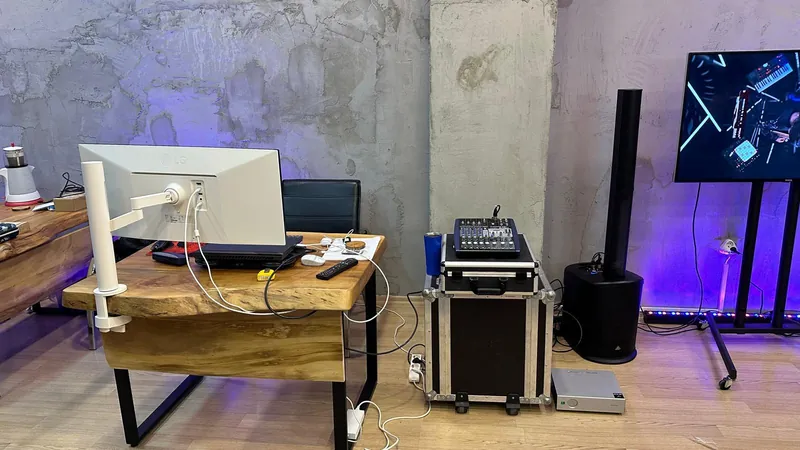 Reji masasında monitör, flight case üzerinde ses mikseri, kolon hoparlör ve yayın ekranı