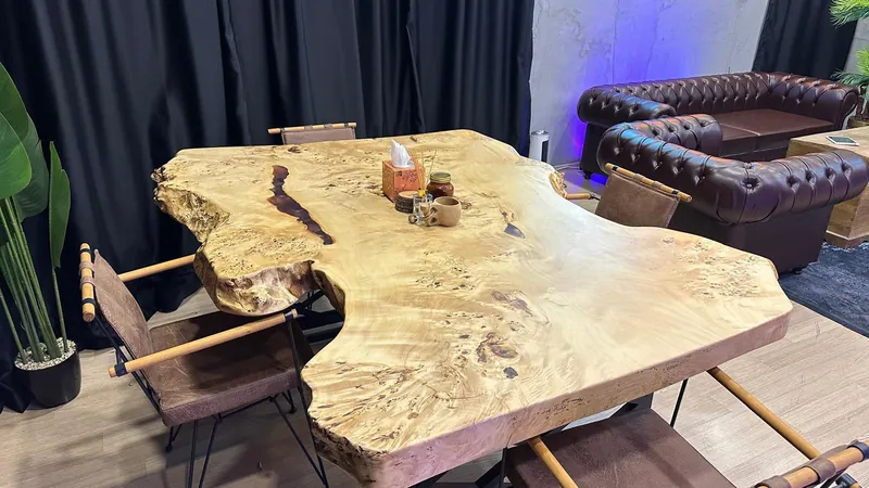 Dört kişilik doğal ahşap toplantı ve podcast masası, arkada Chesterfield koltuk takımı